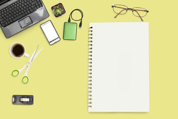 notebook and office accessories on yellow office desk
