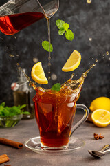 Tea in glass tea cup, levitation. Flying lemons, mint and pouring tea. Action shot of fresh black...