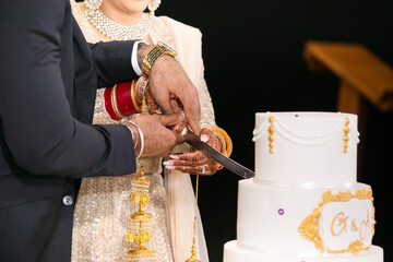 Indian couple's cutting a wedding cake hands close up