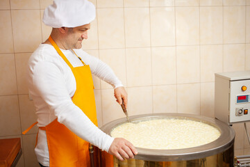 man makes cheese, boils milk in cistern, heating, temperature. Milk folding process, home...