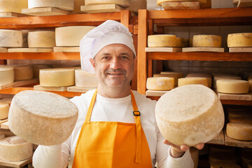 male, man cheese maker businessman, individual entrepreneur, checks cheese in cellar, basement....