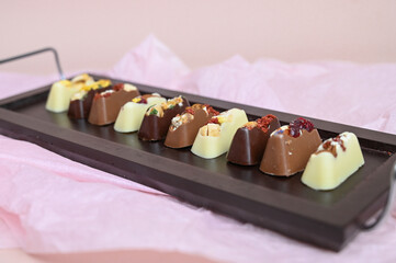 Set of handmade bonbons with berry and nuts filling on a wooden tray. Exclusive handcrafted chocolate candies.