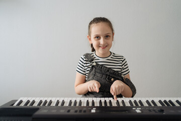 Child playing piano. Kids play music. Classical education for children. Art lesson. Little girl at white digital keyboard. Instrument for young student. Music class in school or at home. High quality