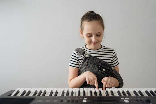 Child playing piano. Kids play music. Classical education for children. Art lesson. Little girl at white digital keyboard. Instrument for young student. Music class in school or at home. High quality - Powered by Adobe