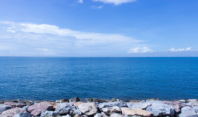 The sea along the rocky coast and the blue sky, Without sea waves and reflections to feel calm and undisturbed.