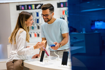 Shopping a new digital device. Happy couple buying a smartphone in store.