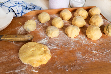 Sweet plum dumpling and piece of yeast dough on kitchen wooden board.