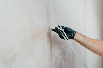 Male worker applying fiberglass surface tissue on the wall