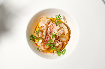 Appetizer with roasted sea scallop and cauliflower. Creamy risotto with scallops and vegetables. Grilled sea scallops in white ceramic plate with harsh shadows. Seafood menu. Summer food.