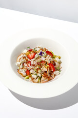 Elegant salad with smoked eel, strawberry and avocado on white table with harsh shadows. Eel salad with berries on white background with shadows of leaves. Romantic dining with fish appetizer.
