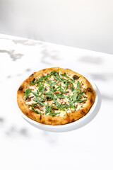 Mushroom pizza with cheese and arugula on white background with shadows. Italian pizza with porcini mushrooms on white table and hard shadows Cheese pizza in trendy style. Modern italian food