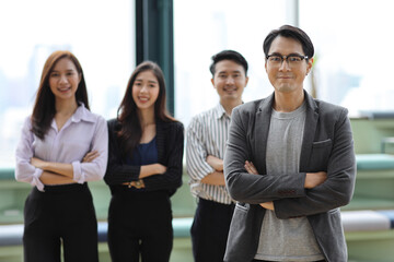 Collaborative process of young asian business people team working together discussing, researching, brainstorming and planning while crossed arms in business office building and city background