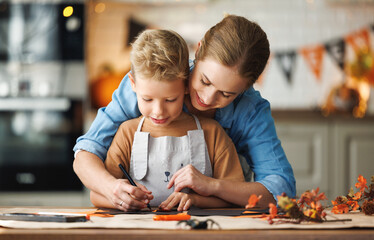 Obraz na płótnie Canvas Happy smiling family mother and son making Halloween home decorations together