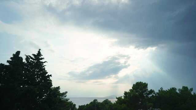 Time lapse footage of beautiful evening dramatic clouds over a sea in Dalmacia seaside. Shot is framed with pine trees in a front.