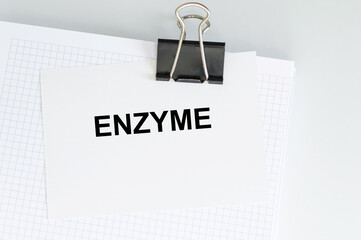 ENZYME text on a card clip to a notepad on a light background
