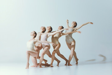 Group of young girls, ballet dancers performing isolated over grey studio background. Expression of freedom