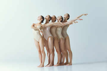 Group of young girls, ballet dancers performing isolated over grey studio background. Standing...