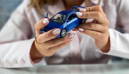 beautiful female hands at the table make conditional protection of a small car.
