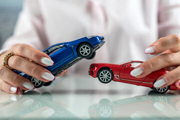 Insurance agent woman simulating an accident with two mini cars on the table.