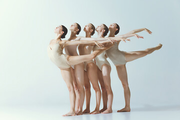 Group of young girls, ballet dancers performing isolated over grey studio background. Flexibility of grace