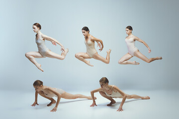 Group of young girls, ballet dancers performing, posing isolated over grey studio background....