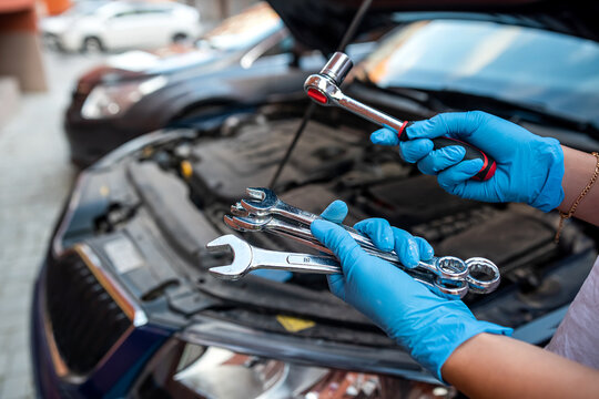 Car mechanic repairman hands repairing car engine of car workshop with wrench and service.