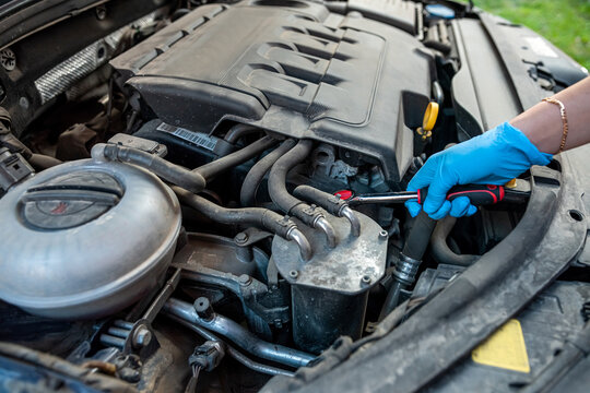 car mechanic or repairman repairs a car engine by hand in a car workshop with a wrench.