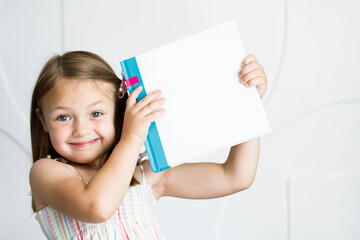 Fototapeta Książka dla dziecka z pustą okładką, dziewczynka trzyma książkę obraz