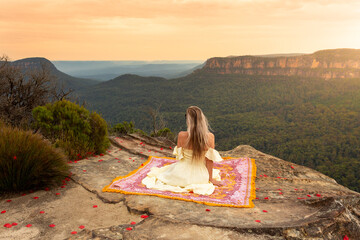 Woman on rug on mountain cliff with vsplendid iews