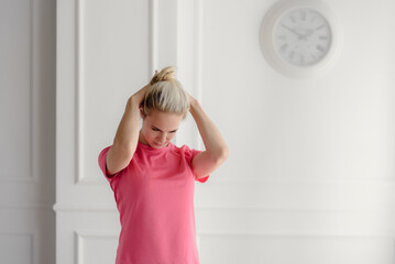 Attractive healthy woman in pink T-shirt warming up in her apartment