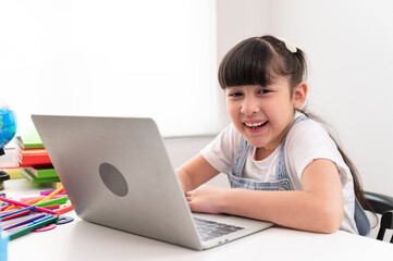 Portrait kids girl doing homework with notebook computer at home	