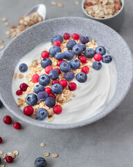 close-up on yogurt with blueberries, cranberries and granola on a light background, greek yogurt, healthy breakfast