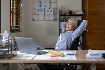 Business asian woman relaxing with hands behind her head and sitting on an office chair