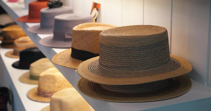 Steadicam shot: New seasonal collection of summer straw hats on shelves, display for sale in the headdress shopping store. Headwear. Headgear. Clothing store showcase with variety of caps and hats