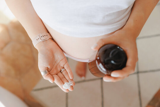 Top view Pregnant woman applies cream on her stomach to moisturize skin and improve elasticity to prevent stretch marks