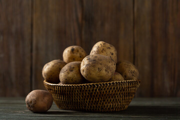 Close-up of fresh uncooked potato roots in a basket on wooden table