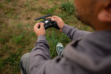 Man hands remote control sticks of and fly on FPV drone at drone racing competition.