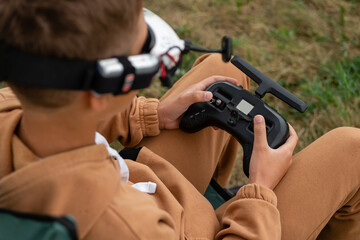 Child hands remote control sticks of and fly on FPV drone at drone racing competition.