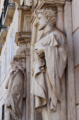 Facade of a historical building in the old town of Lisbon, Portugal, Europe. Statues, sculptures, figures, and beautiful ornaments decorate an old house's entrance. Ancient stone statues. 