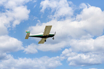 Single engine ultralight plane flying in the blue sky with white clouds