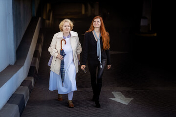 Two women together - blonde in light and redhead in dark clothes. Cosplay - female version of Angel and Demon (Good Omens)