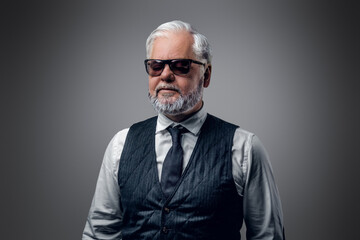 Obraz premium Portrait of cool old man with sunglasses dressed in waistcoat and white shirt.