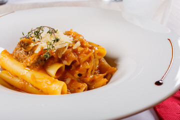 Piatto di pasta con sugo di genovese napoletana fatta con carne e cipolla e scaglie di parmigiano servito in un ristorante 