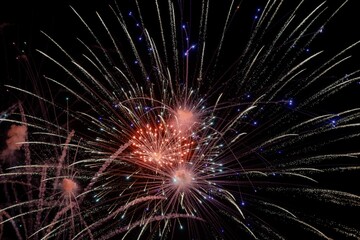 Sparkly burst of a red firework and blue sparkles in the night sky