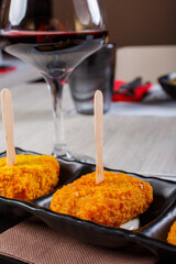 Crocchè di patate fritti a forma di quadrato serviti in un ristorante come antipasto con un calice di vino rosso