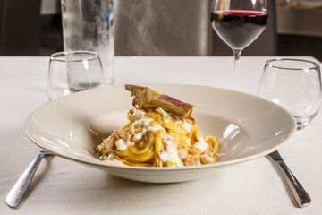 Piatto di pasta con carciofi, salsiccia e formaggio fuso servito in un ristorante napoletano