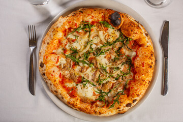 Pizza napoletana con tonno, cipolla, mozzarella, sugo di pomodoro e prezzemolo servita in una pizzeria