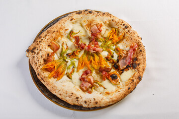 Pizza napoletana con pancetta croccante, fiori di zucca e mozzarella di bufala servita in una pizzeria 