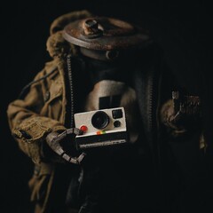 Closeup shot of a headless soldier miniature holding an old camera