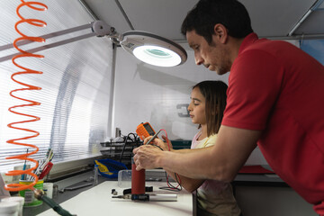 Father teaching his daughter the correct use of tools in his workshop